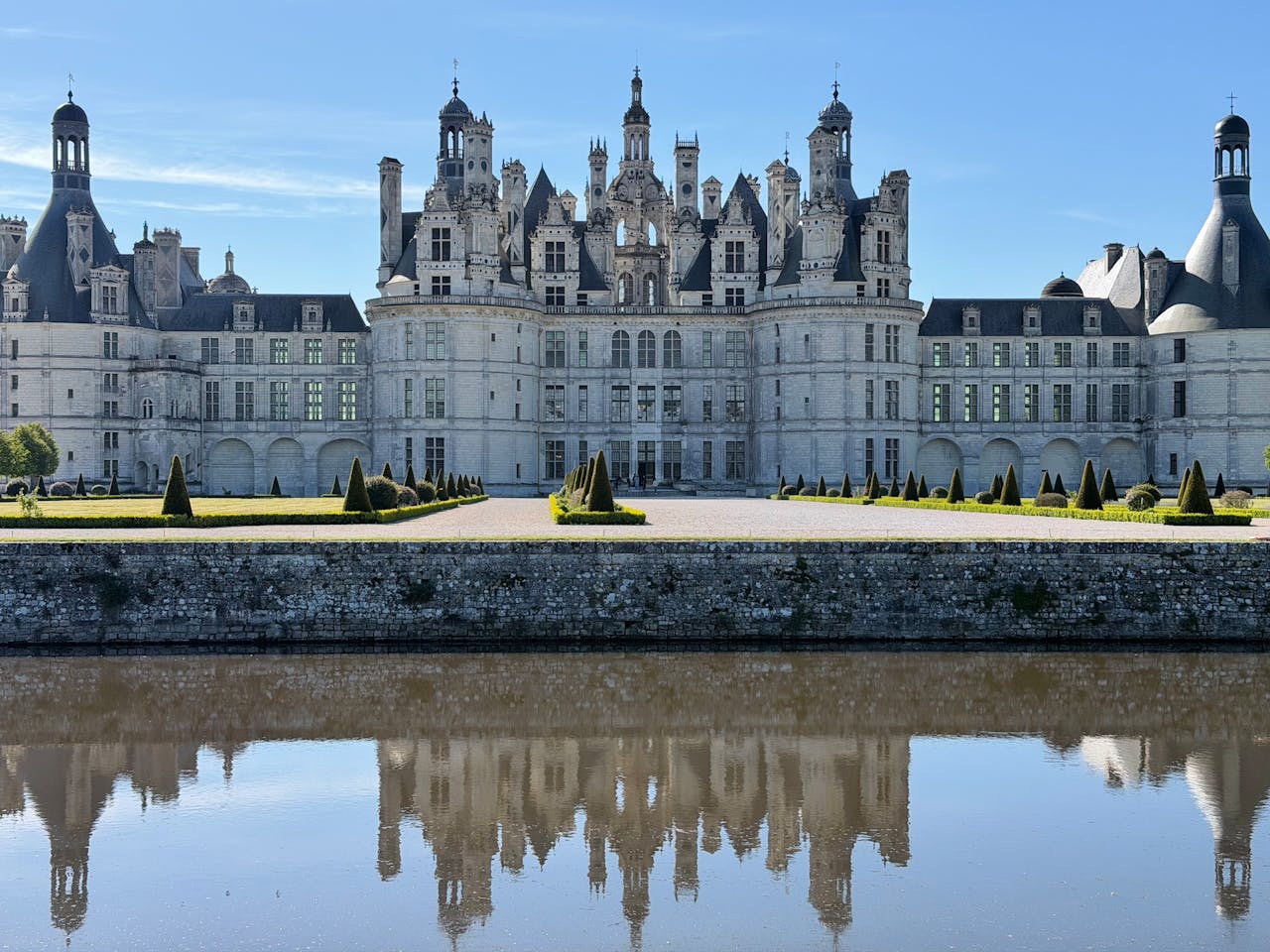Majestic Château de Chambord mirrored in the calm waters on a clear day.